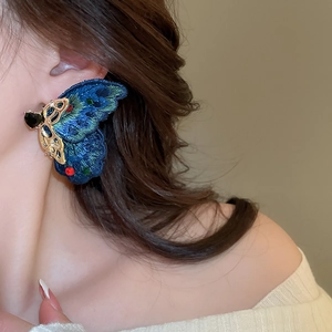 Detail of blue embroidered butterfly earring with colorful rhinestones on model