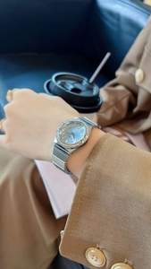 Detail of light blue dial watch with crystal bezel worn in a stylish cafe setting