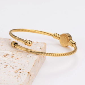 Detail of warm gold stainless steel open bangle featuring unique spiral twisted texture