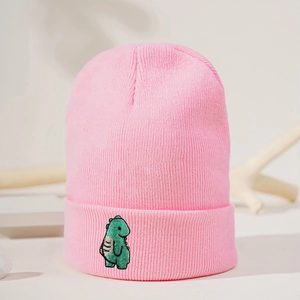 Detail einer rosa Strickmütze mit grünem Dino-Stick auf weichem, warmem Material