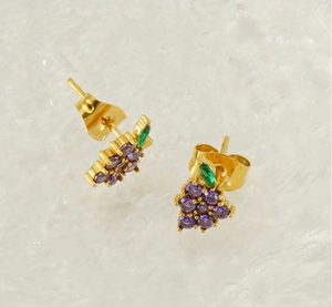 Detailed view of grape-shaped gold stud earrings with purple crystals and green leaf accent