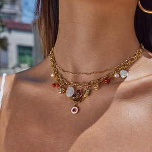 Layered stainless steel necklace with pearl, heart, and flower charms on a model