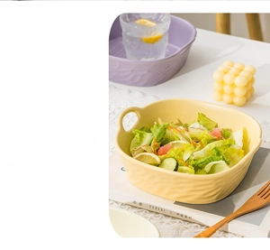Detail of light yellow ceramic baking bowl with textured relief and dual handles