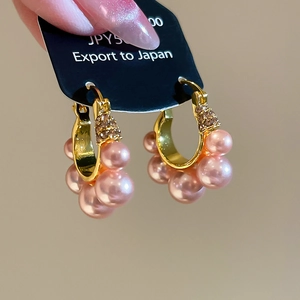 Détail macro de boucles d'oreilles en grappe de perles roses avec cristaux étincelants