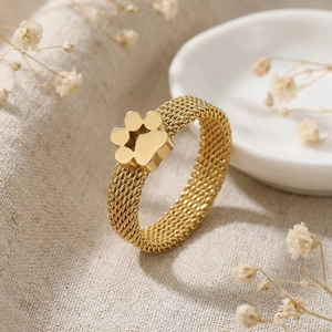 Detail of a golden mesh ring featuring a 3D cat paw floral design on natural linen backdrop