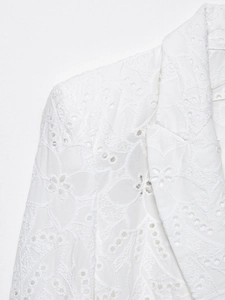 Détail d'un blazer en dentelle de coton blanc avec broderie florale et œillets