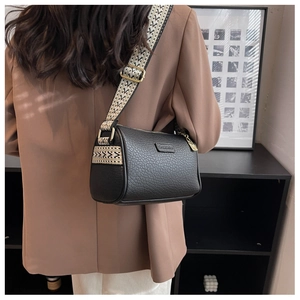 Detail der schwarzen Zylindertasche aus Leder mit besticktem Gurt am Model getragen