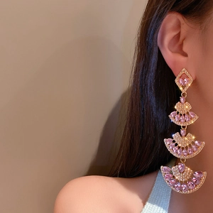 Detail of pink crystal fan earrings in gold finish with Art Deco tassel design on model