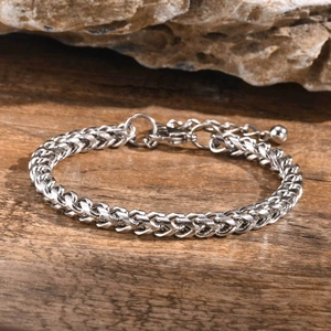 Detailed view of silver stainless steel curb chain bracelet on a rustic wooden texture
