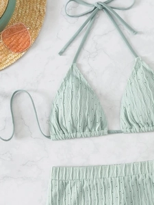 Detail of mint green bikini fabric with wave texture and halter neck straps on marble