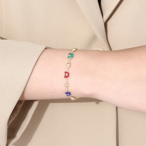 Detailaufnahme der bunten Schmetterlingsanhänger am goldenen Armband direkt am Handgelenk