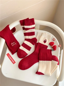 Detail of red and white knitted cashmere socks with embroidered slogans and festive patterns