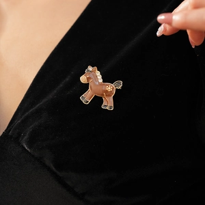 Detail of a brown enamel horse brooch with sparkling rhinestones on black velvet fabric