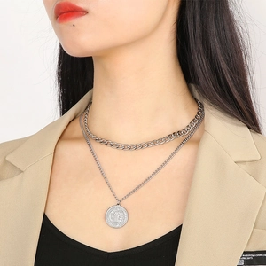 Double-layered silver Cuban chain necklace with vintage coin pendant on female model