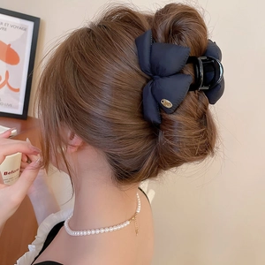 Detailed view of a large black bow hair claw clip styled on a woman's hair in a French twist