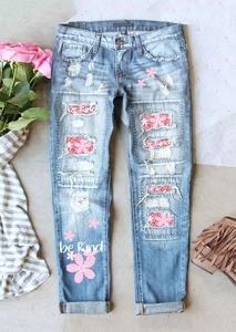 Détail de jean bleu clair déchiré avec patchs floraux et imprimé Be Kind