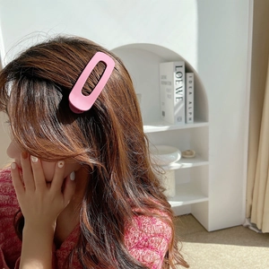 Close-up of a matte pink hollow oval hair clip worn by a model in a natural lifestyle setting
