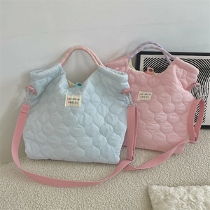 Détail de sacs matelassés macaron en bleu et rose avec des anses en corde à carreaux