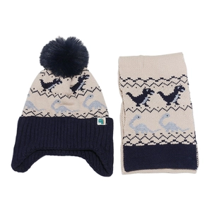 Détail du motif de dinosaure tricoté sur l'ensemble bonnet et écharpe d'hiver beige