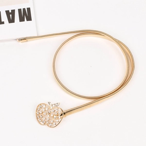 Détail d'une ceinture dorée élastique à ressort avec une boucle pomme luxe en strass