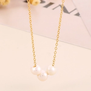 Macro shot of 18K gold plated chain with three round white pearls on a minimalist necklace