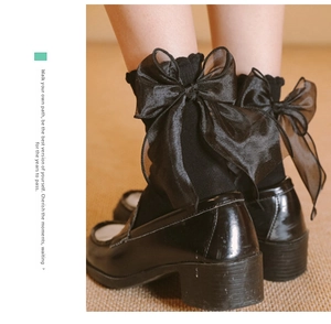 Detail of black knit calf socks featuring a large sheer organza bow on the back cuff
