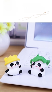 Cute mini panda figurines with sun hat and lotus leaf on a laptop desk setup