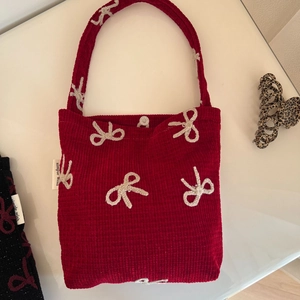 Détail du sac à main en velours côtelé rouge avec nœud au crochet et fermoir pression