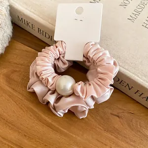 Chouchou élégant en satin rose avec une grande perle blanche sur fond de livre vintage