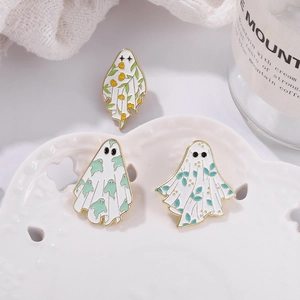 Detailed set of three ghost and maple leaf enamel pins on a decorative white porcelain plate