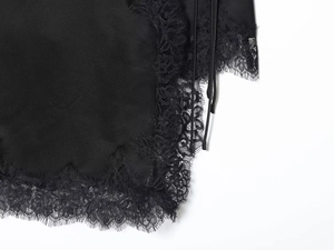 Detail of elegant black satin fabric with intricate eyelash lace trim and delicate straps