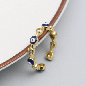 Macro view of gold evil eye open ring with blue enamel and cubic zirconia on a white plate