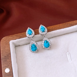 Detail of vintage silver drop earrings with blue turquoise stone in a wooden jewelry box