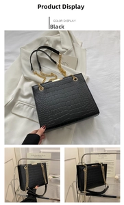 Detail of black crocodile embossed tote bag featuring a golden chain strap and luxury texture
