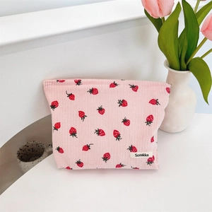 Sac fourre-tout en velours rose à fraises sur bureau avec tulipes et vase blanc