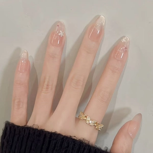 Nahaufnahme eines goldenen Schmetterlingsrings mit Zirkonia und floraler Nagelkunst