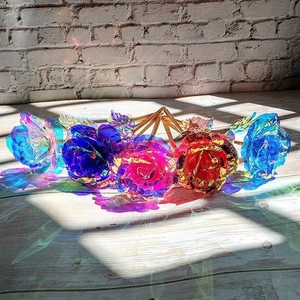 Artistic detail of five colorful gold foil roses on wooden floor with sunlight shadows