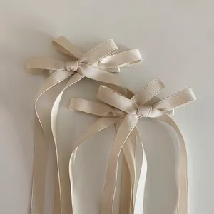 Gros plan de nœuds de cheveux en satin champagne avec de longs rubans fluides pour fille