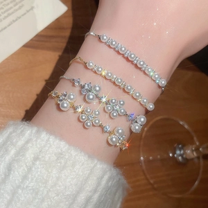 Detailed view of layered pearl bracelets with zircon flowers on a female wrist
