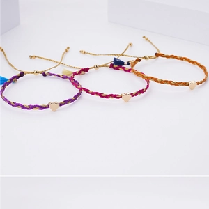 Detail of colorful braided friendship bracelets featuring golden heart-shaped charms
