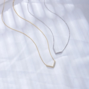 Close-up of V-shaped pendants in gold and silver finish with sparkling diamond inlay