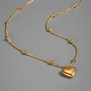 Macro de collier pendentif cœur doré avec chaîne à billes en acier titane poli brillant