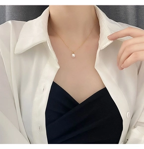 Close-up of a minimalist gold chain necklace with a single white pearl on a female model