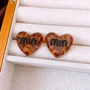 Tortoiseshell acetate heart stud earrings with black miu lettering in a velvet jewelry box