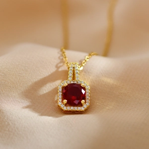 Macro detail of a square gold pendant with a central red ruby and small white diamonds