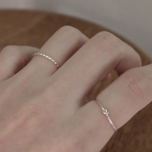 Close-up of minimalist 925 silver beaded and knotted rings worn on a hand