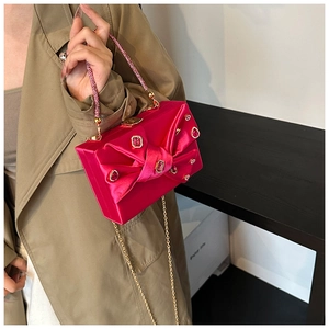 Pink silk evening bag featuring a rhinestone bow detail and sparkling crystal handle