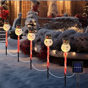 Solar powered snowman candy cane pathway lights in snow-covered garden setting