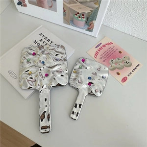 Detail of silver handheld mirrors featuring vintage ripple texture and colorful gemstones