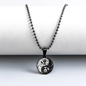 Macro detail of round Tai Chi pendant with rose engraving on black bead chain